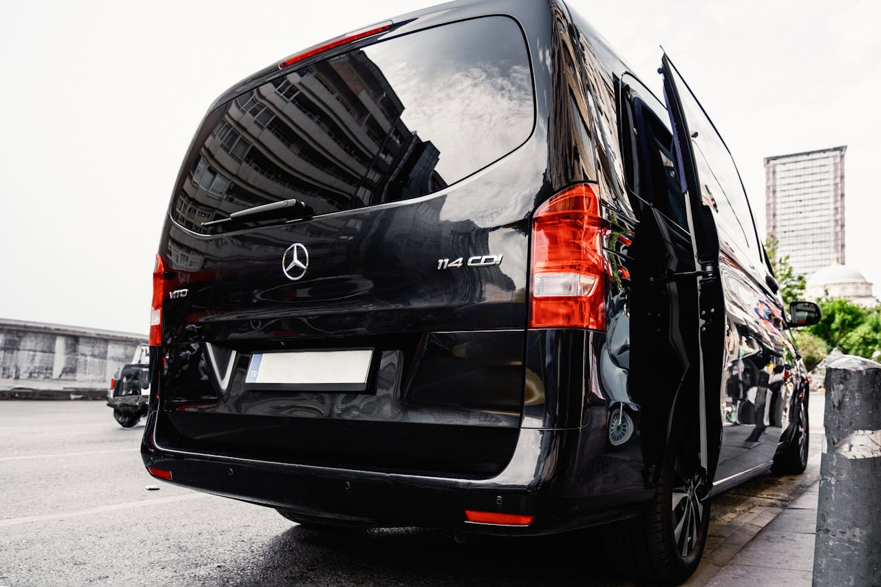 Rear view of a black luxury van on a city street, showcasing urban lifestyle.
