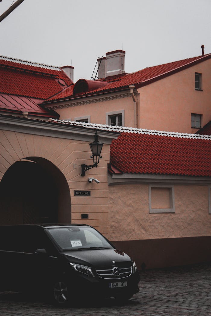 Scenic urban view featuring buildings with red roofs and a Mercedes van parked on a cobblestone street.